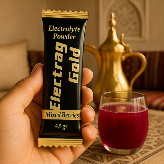 A sachet of Electrag Gold sugar-free electrolyte powder with a glass of mixed berries hydration drink beside a traditional Arabic coffee dallah in Doha, symbolizing hydration balance in the Gulf.
